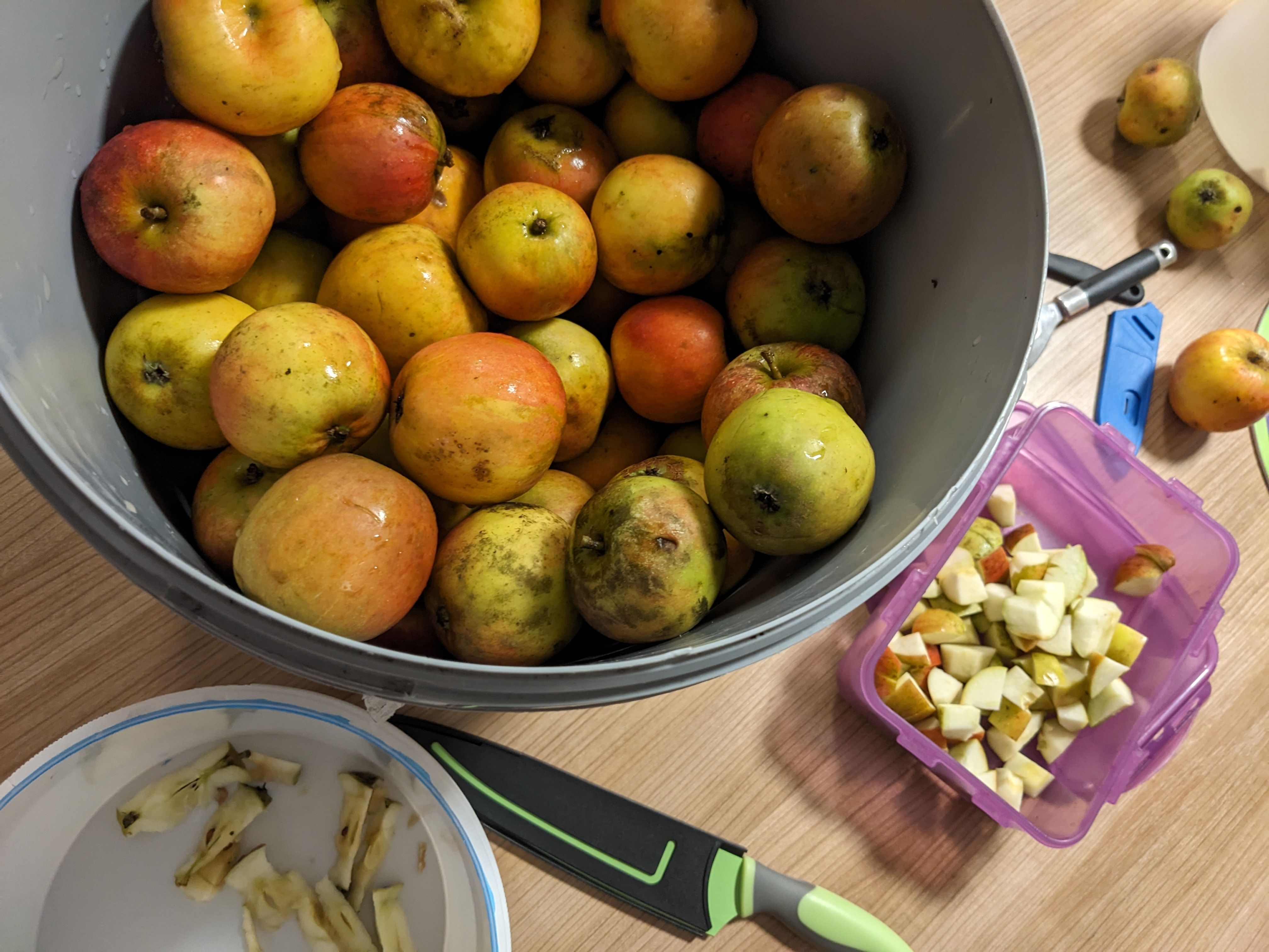 Äpfel in einer großen Schüssel, danebel Äpfel in Stücke geschnitten in einer Dose