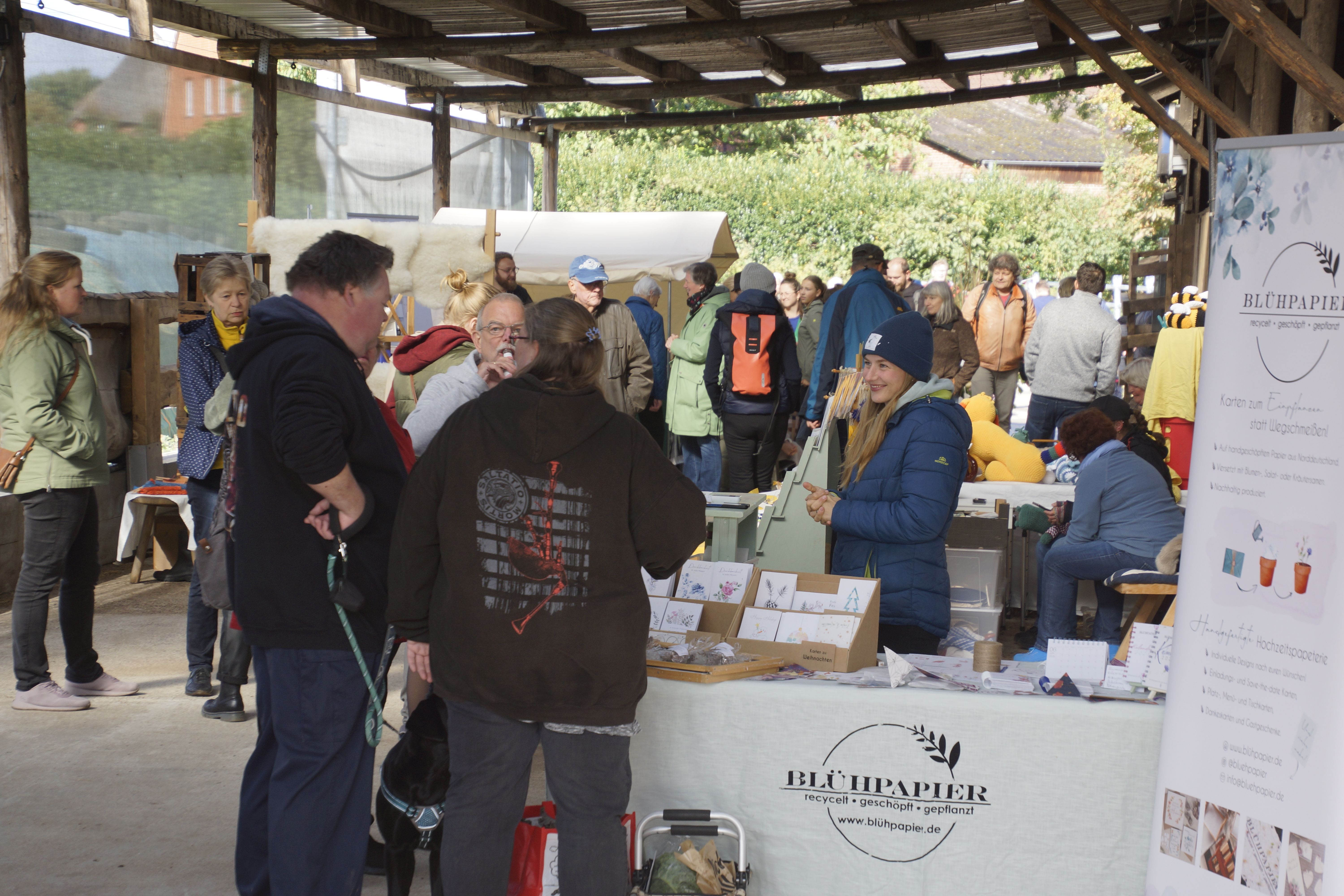Viele Menschen in einer Scheune mit Ständen